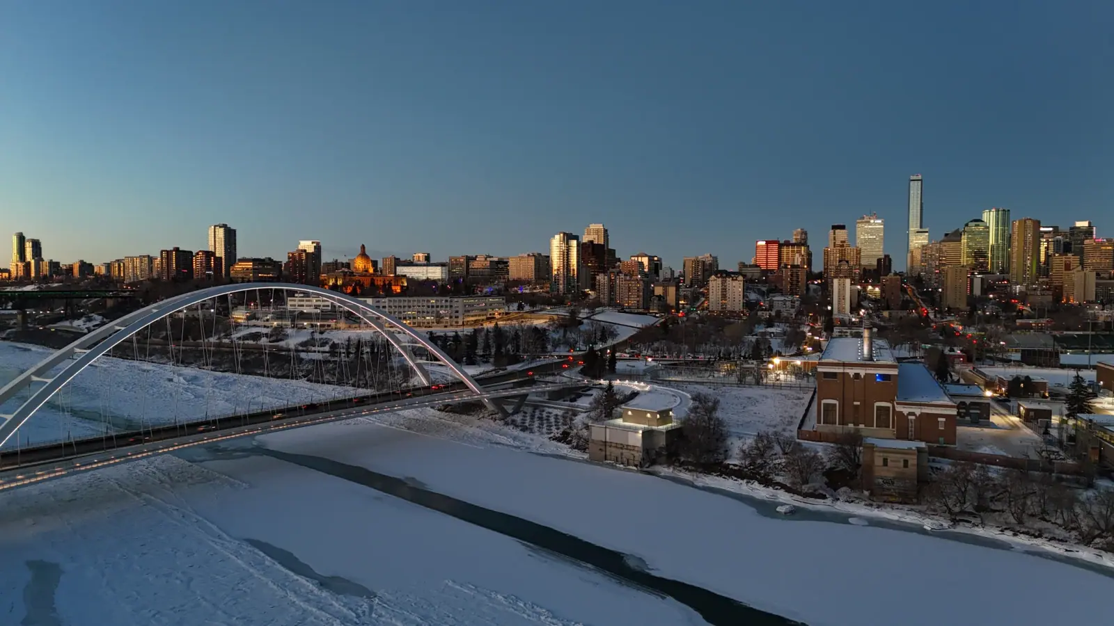 Winter cityscape with illuminated bridge and a frozen river